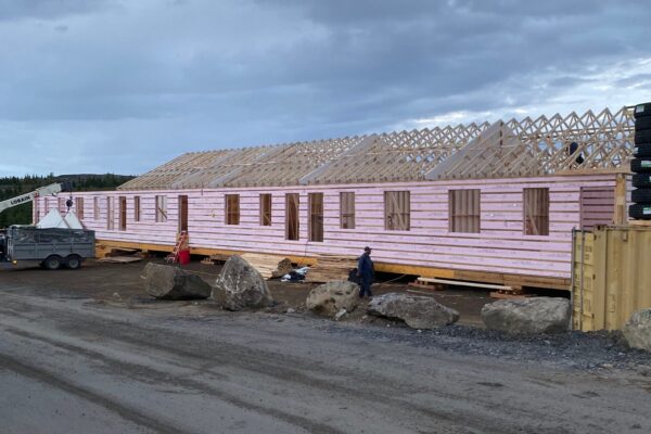 Partially constructed wooden building under cloudy sky.