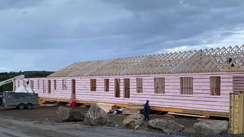 Wooden building under construction with cloudy sky.